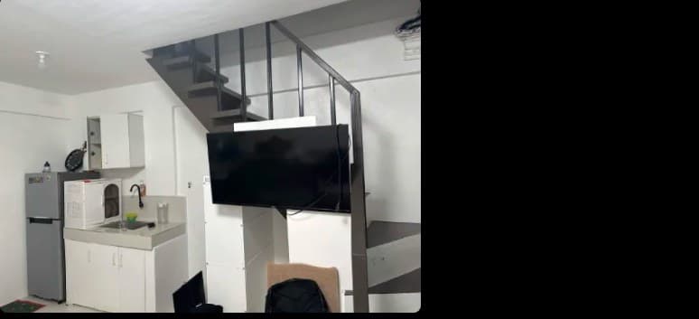 A small apartment with a kitchen, a wall-mounted TV and stairs